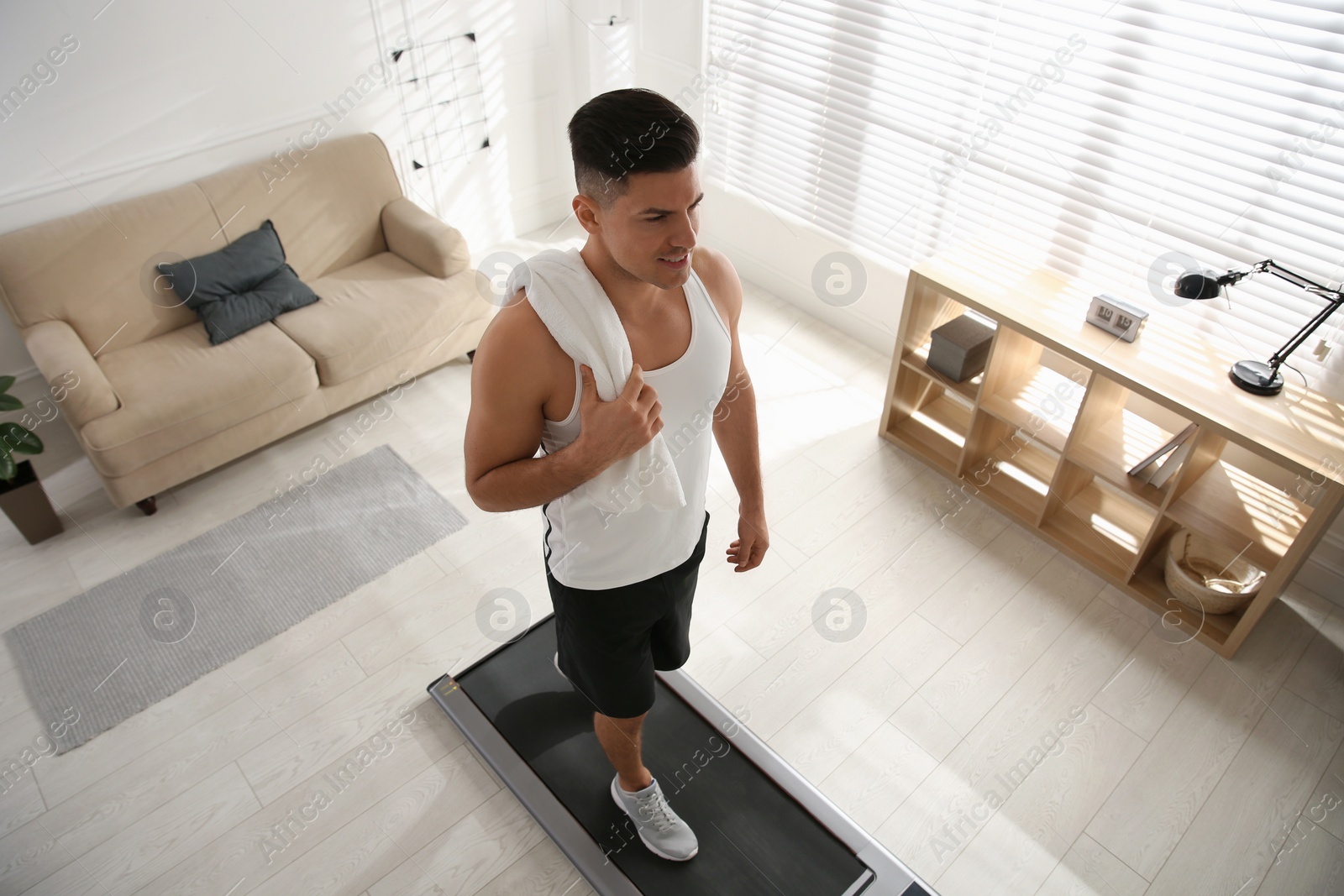 Photo of Sporty man training on walking treadmill at home