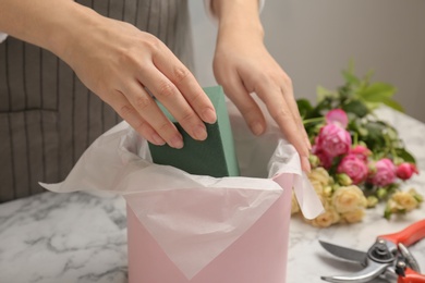 Female florist using floral foam for work at table