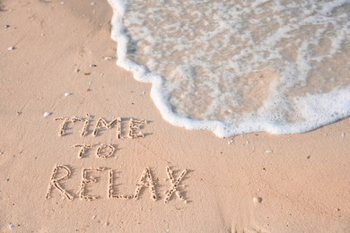 Photo of Phrase Time to relax written on sand at beach