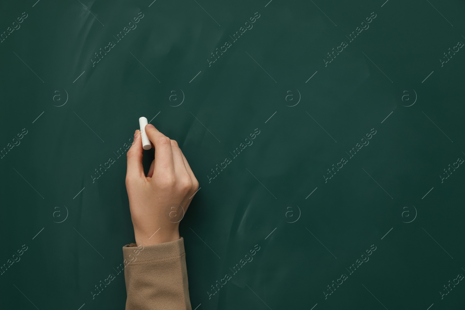 Photo of Woman with white chalk near green board, closeup. Space for text