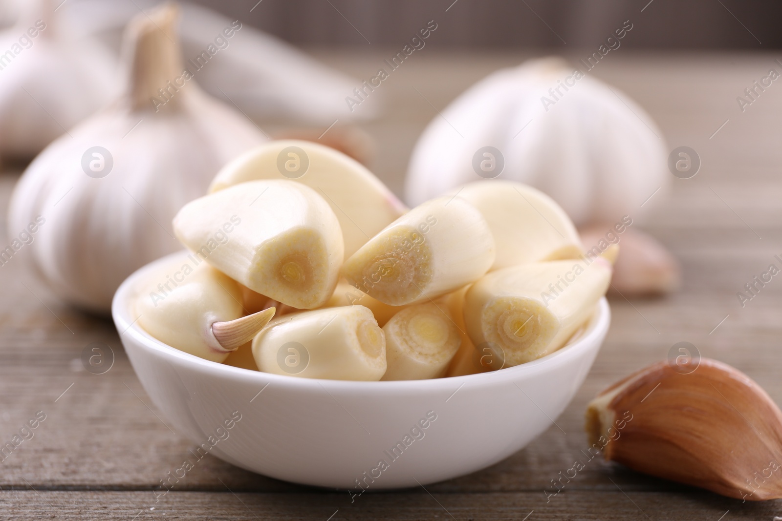 Photo of Aromatic garlic cloves and bulbs on wooden table, closeup