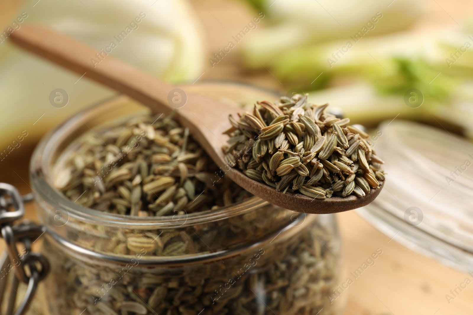 Photo of Jar and spoon with fennel seeds on table, closeup