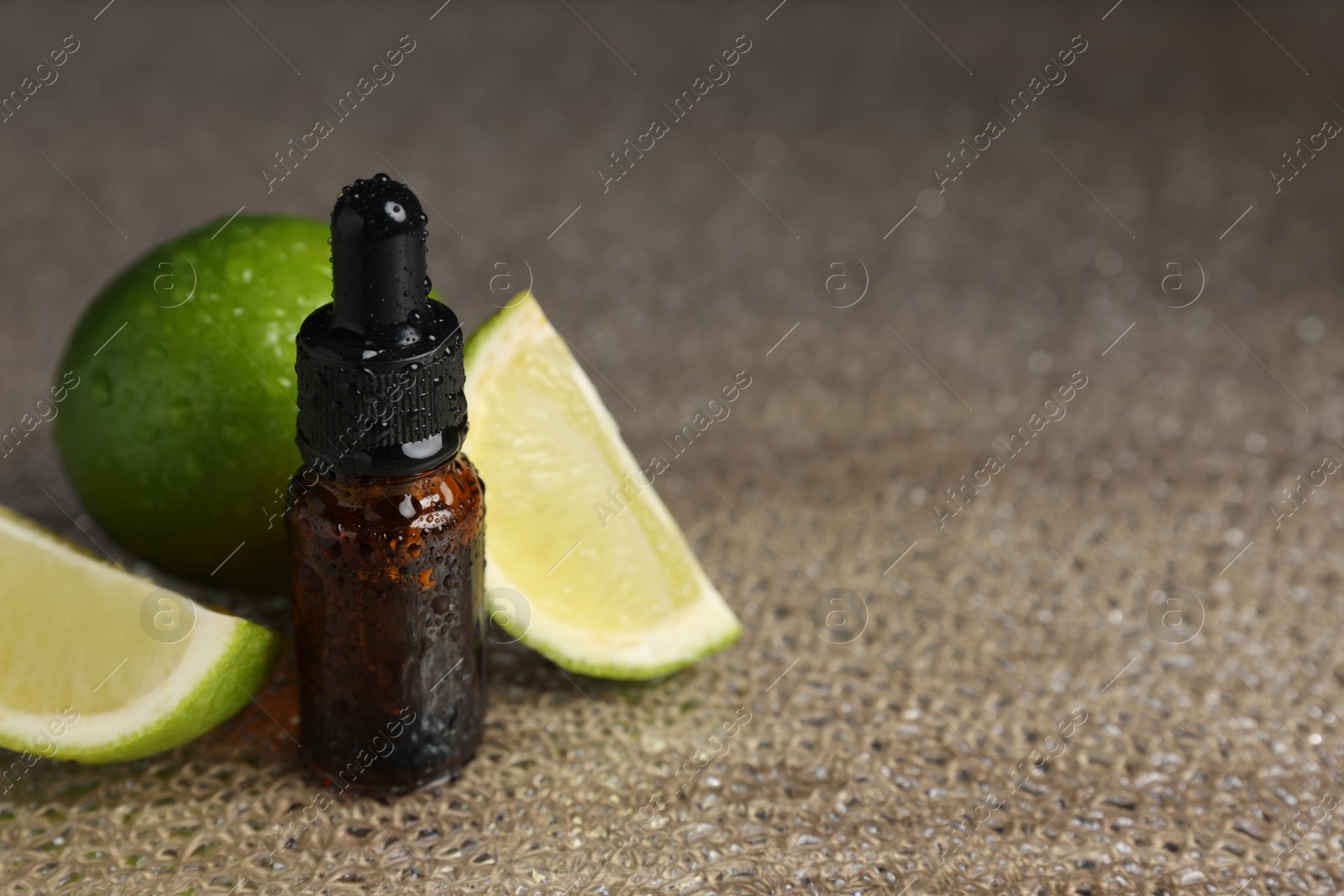 Photo of Bottle of organic cosmetic product and sliced lime on wet surface, space for text