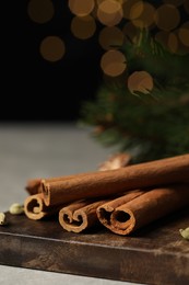 Photo of Board with cinnamon sticks on light table, closeup. Space for text