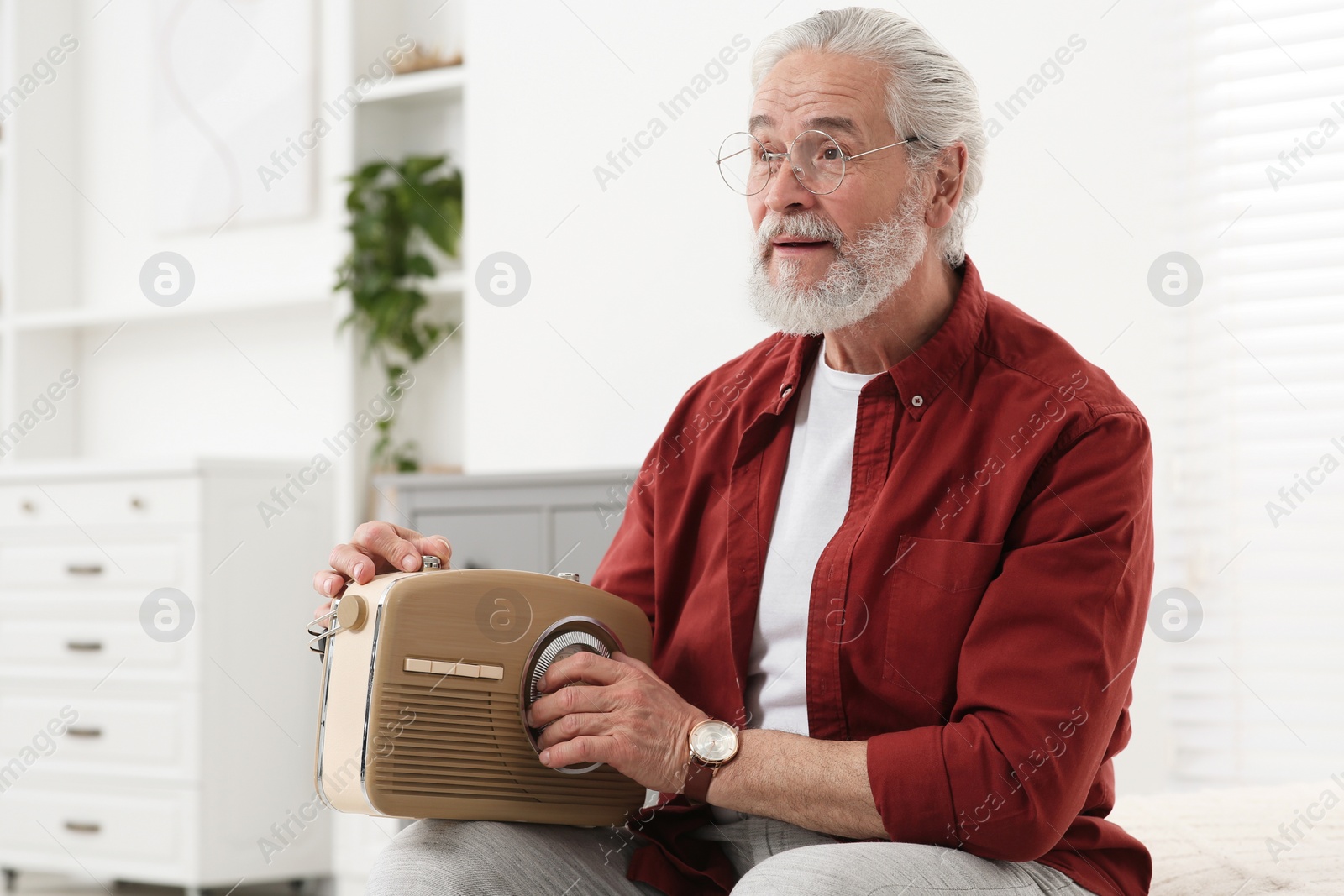 Photo of Senior man with retro radio receiver at home