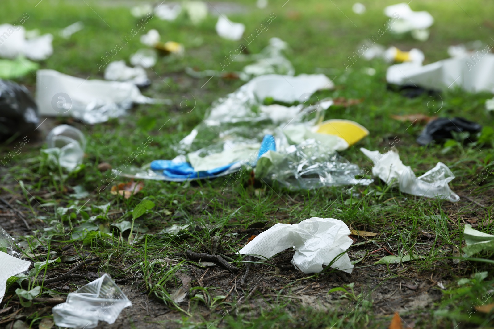 Photo of Different garbage scattered on green grass outdoors