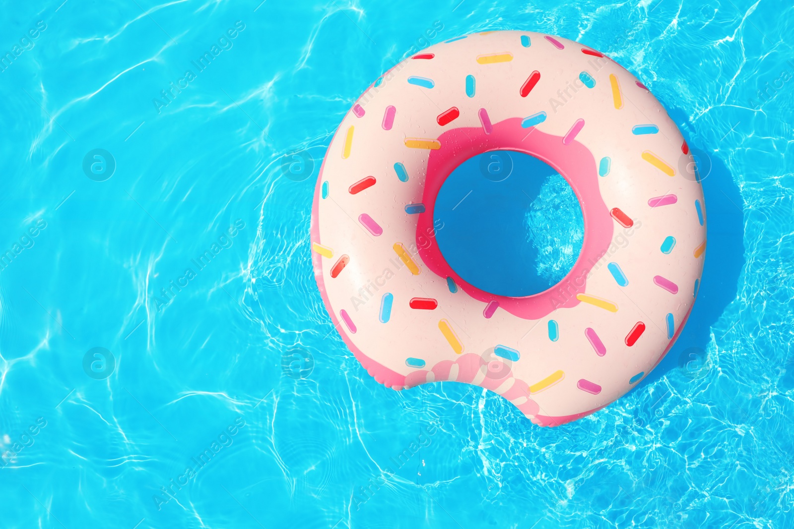 Photo of Inflatable ring floating in swimming pool on sunny day, top view with space for text