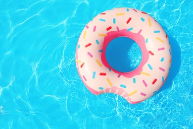 Photo of Inflatable ring floating in swimming pool on sunny day, top view with space for text