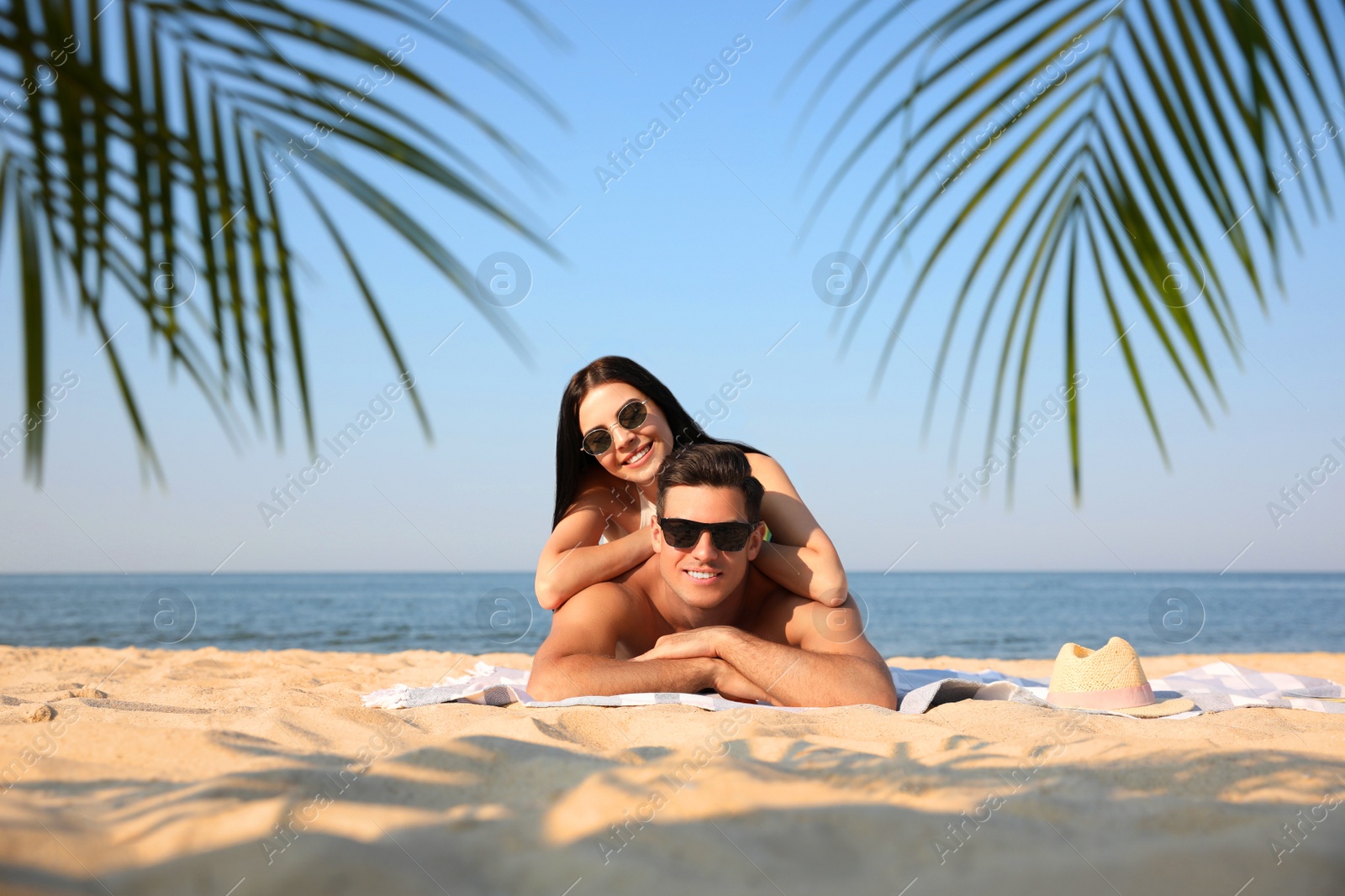 Photo of Happy couple resting on sunny beach at resort