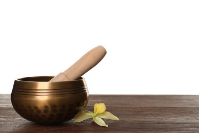 Golden singing bowl, mallet and flower on wooden table against white background, space for text