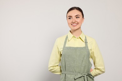 Photo of Beautiful young woman in clean apron with pattern on light grey background. Space for text