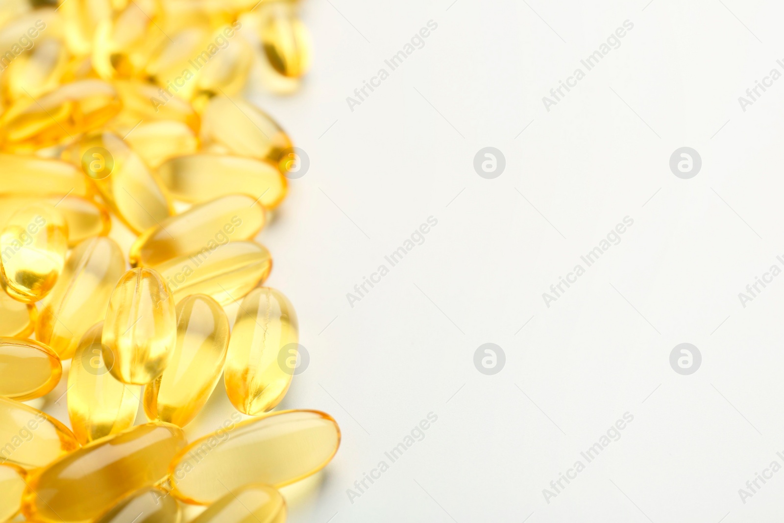 Photo of Yellow vitamin capsules on white background, closeup. Space for text