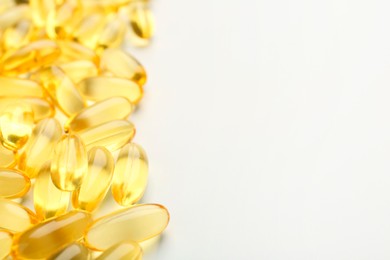 Yellow vitamin capsules on white background, closeup. Space for text