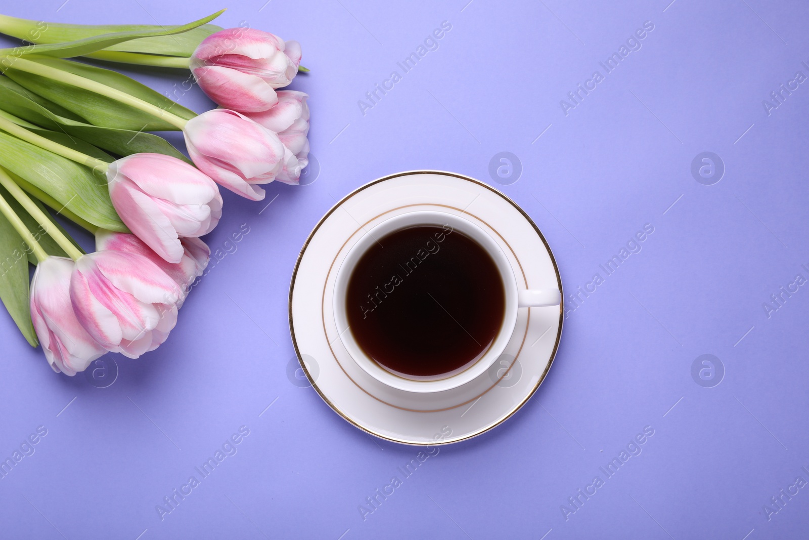 Photo of Cup of coffee and beautiful tulips on light purple background, flat lay