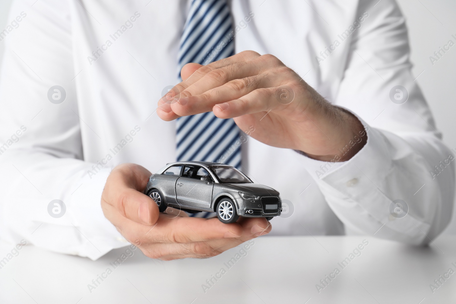 Photo of Male insurance agent holding toy car, closeup