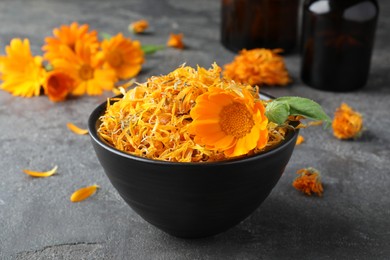 Bowl of dry and fresh calendula flowers on grey table