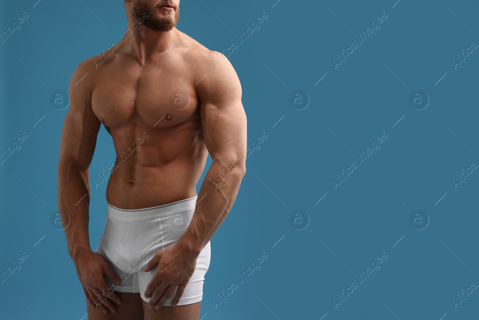 Photo of Muscular man showing abs on light blue background, closeup and space for text. Sexy body