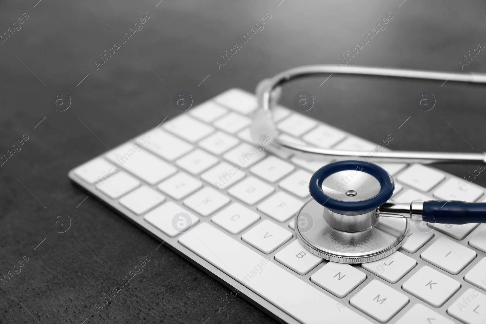 Photo of Modern keyboard and stethoscope on table. Technical support concept