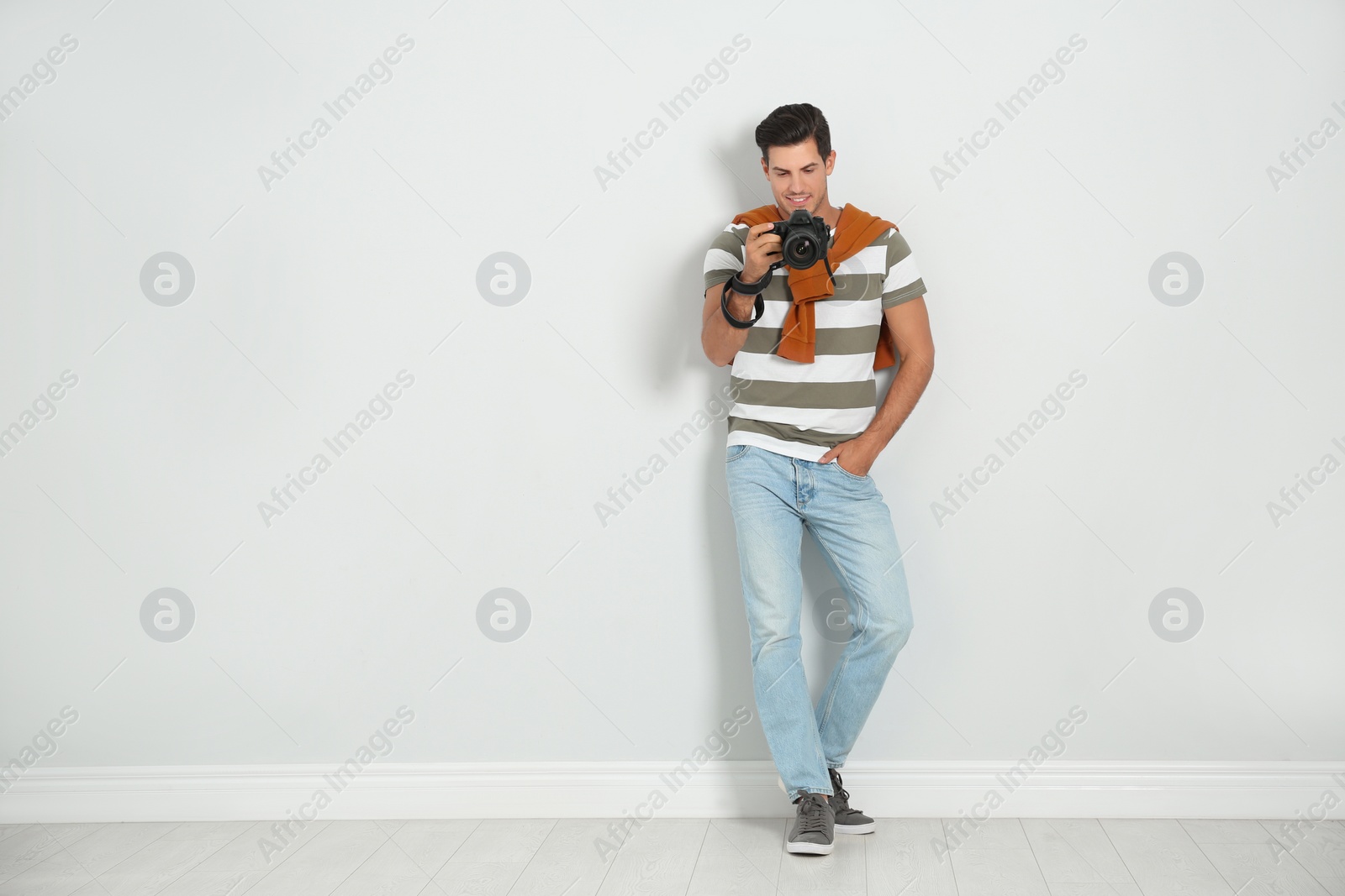 Photo of Professional photographer working near white wall in studio. Space for text