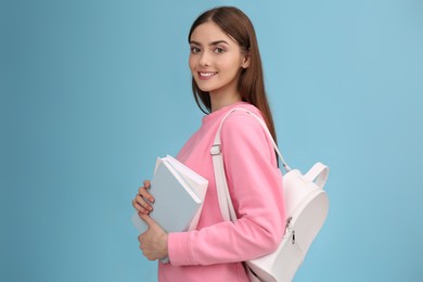 Teenage student with books and backpack on turquoise background