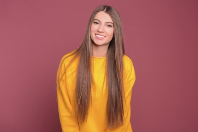 Photo of Portrait of young woman with long beautiful hair on color background