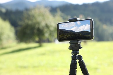 Taking photo of beautiful mountain landscape with smartphone mounted on tripod outdoors, space for text