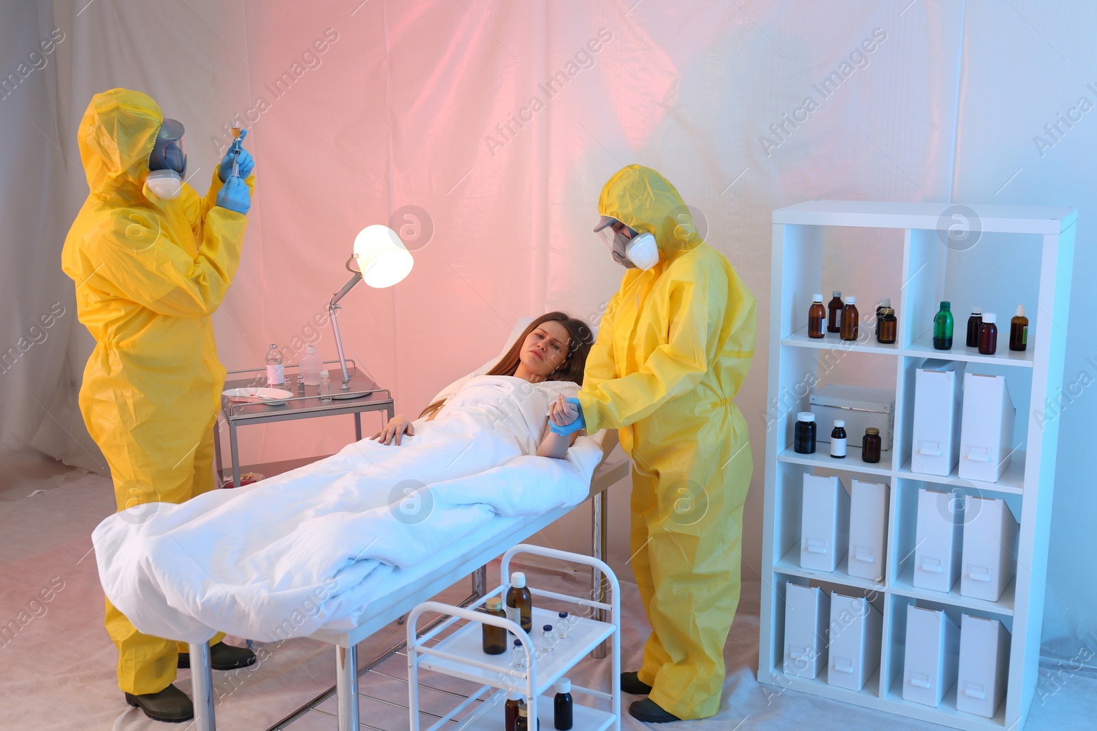 Photo of Paramedics wearing protective suits examining patient with virus in quarantine ward