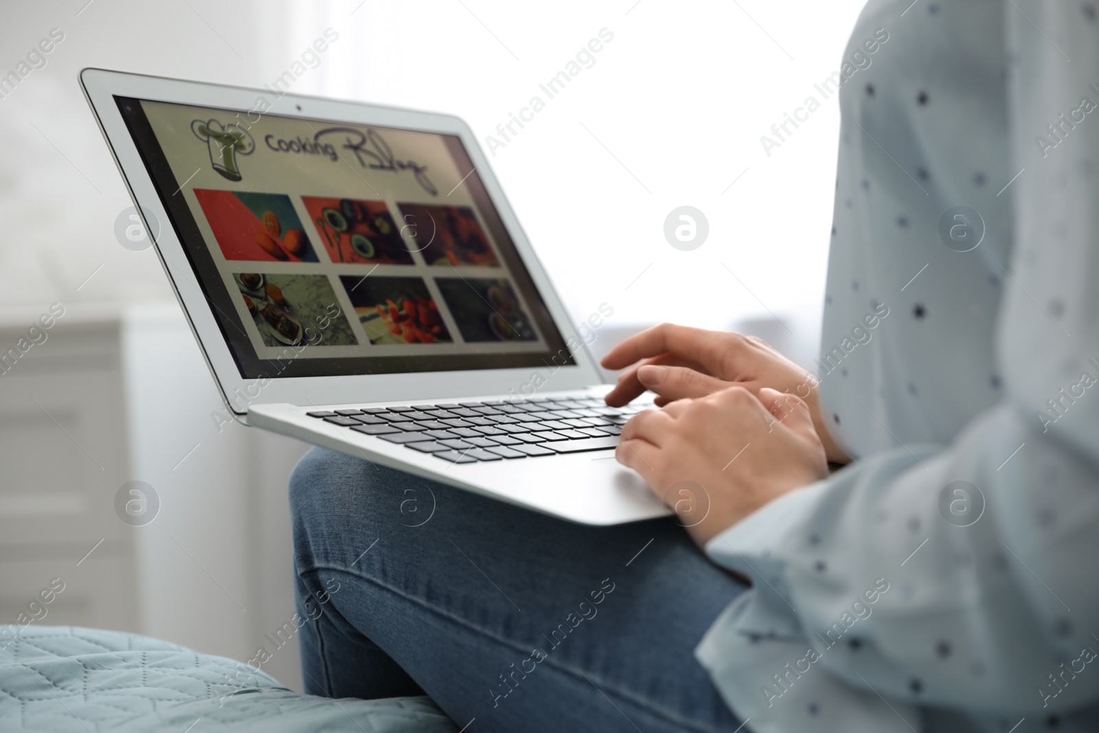 Photo of Woman browsing cooking blog on laptop at home, closeup