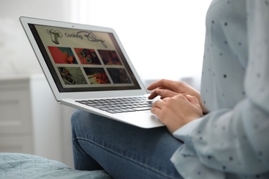 Photo of Woman browsing cooking blog on laptop at home, closeup