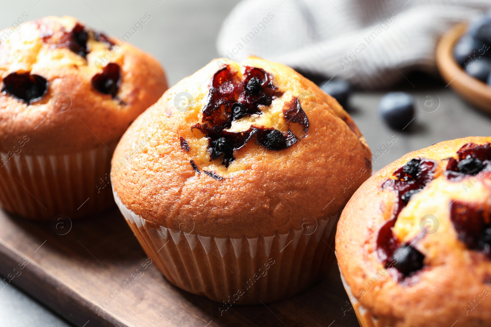 Photo of Tasty blueberry muffins on wooden board, closeup view