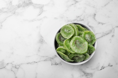 Photo of Bowl of dried kiwi on marble background, top view with space for text. Tasty and healthy fruit