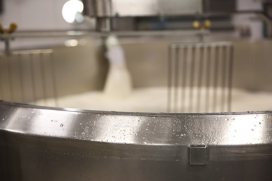 Pouring milk into curd preparation tank at cheese factory, closeup