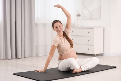 Pregnant woman doing exercises on yoga mat at home