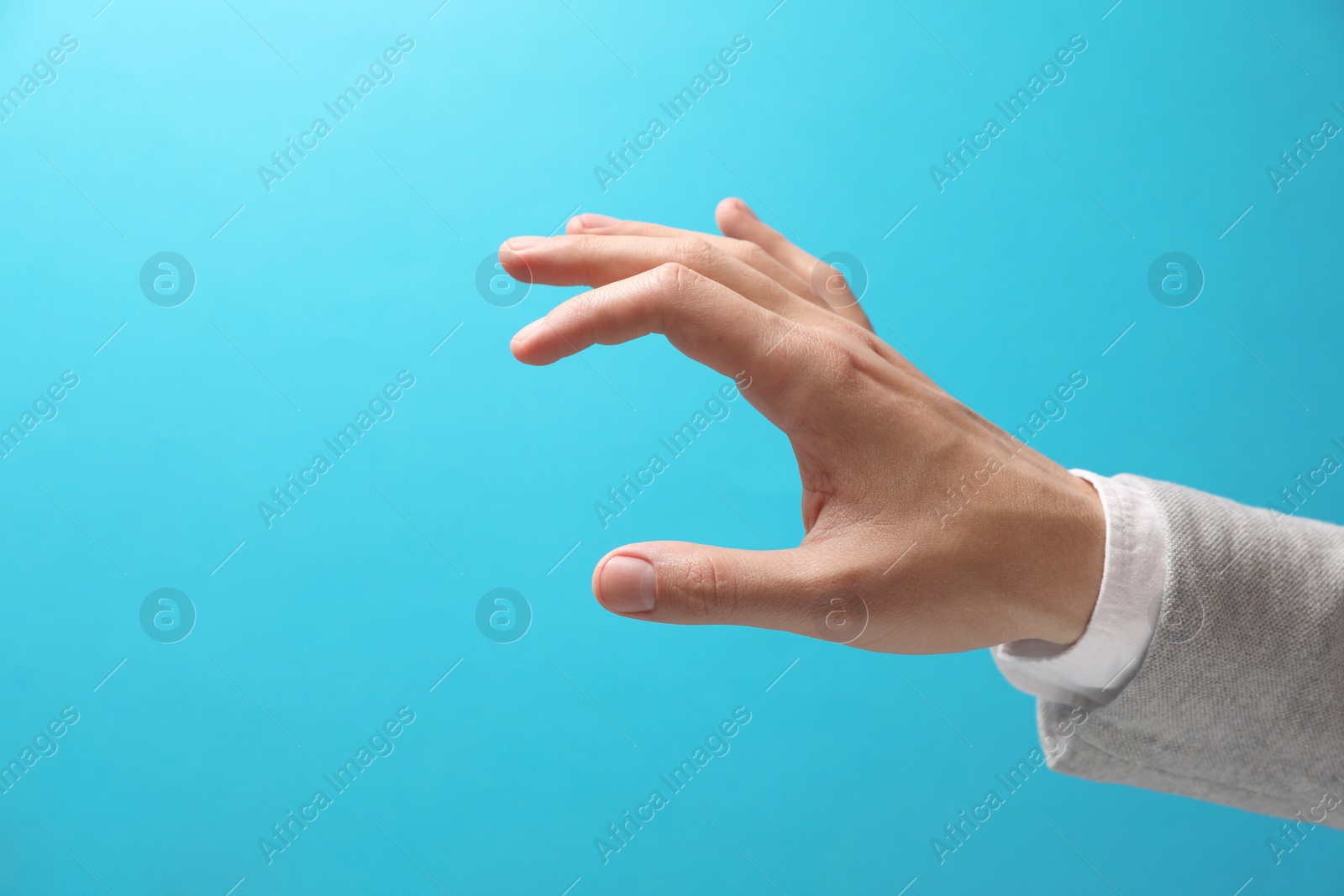 Photo of Man holding something in hand on light blue background, closeup. Space for text