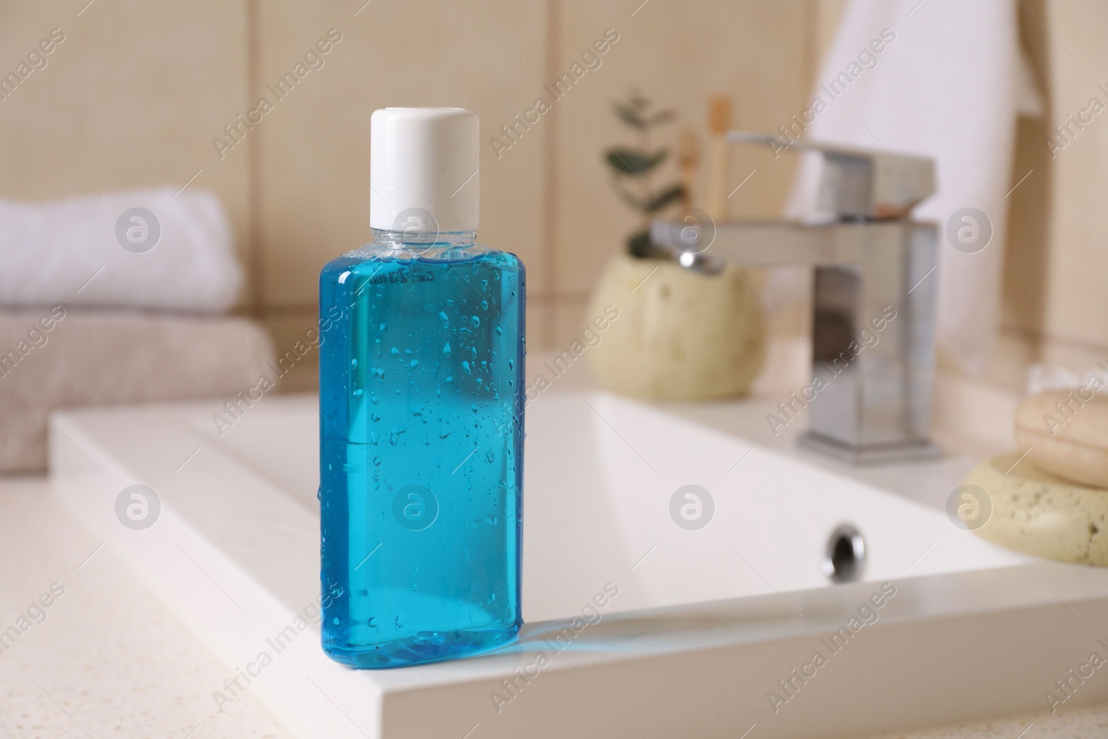 Photo of Fresh mouthwash in bottle on sink in bathroom, closeup