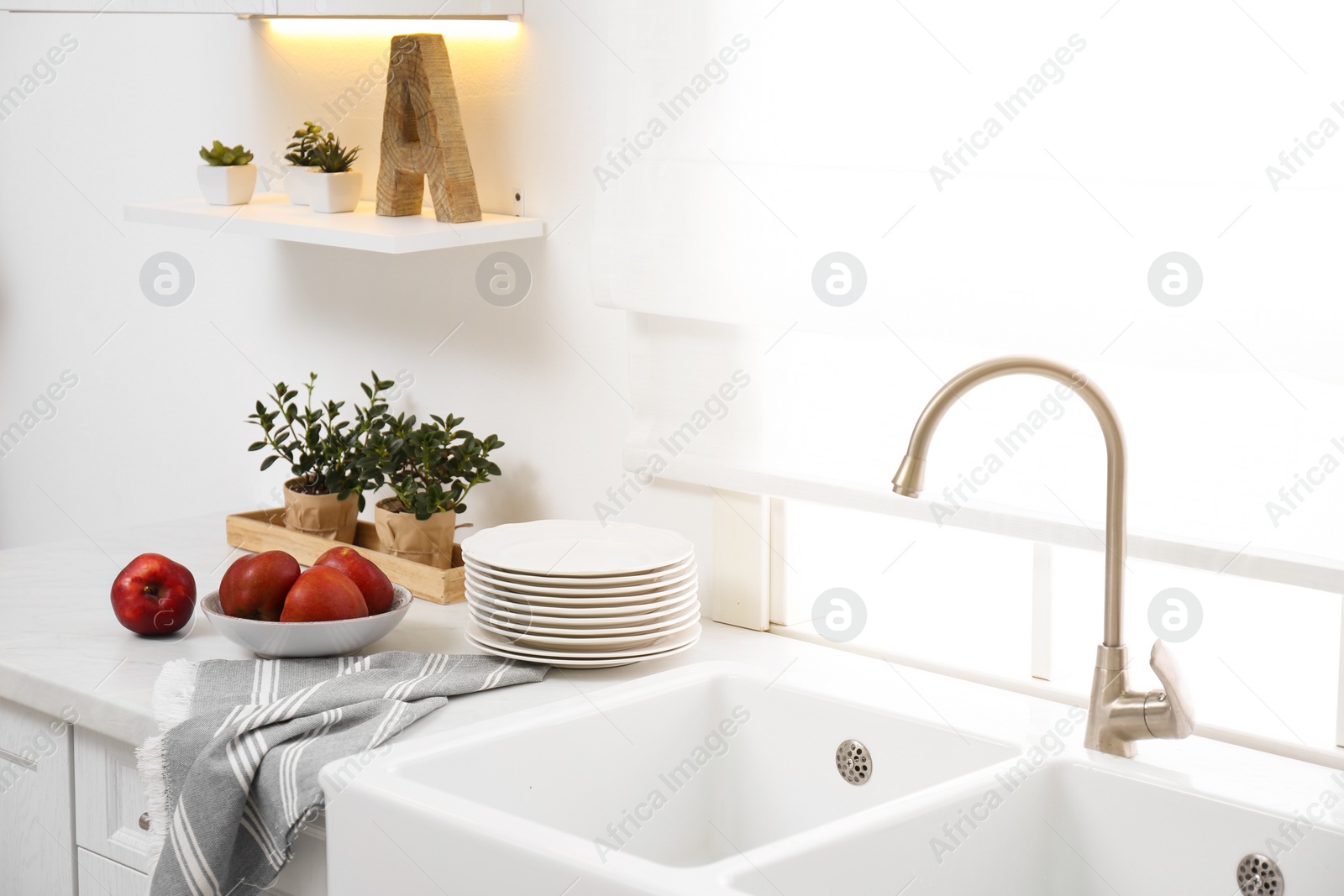 Photo of Modern kitchen interior with bowl full of ripe apples on counter