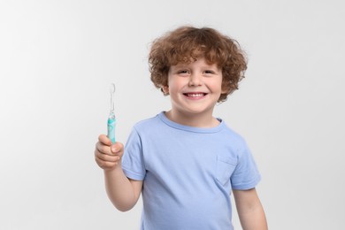 Cute little boy holding electric toothbrush on white background