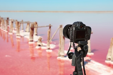 Professional camera with tripod near pink lake