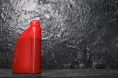 Photo of Motor oil in red canister on black table near dark wall, space for text