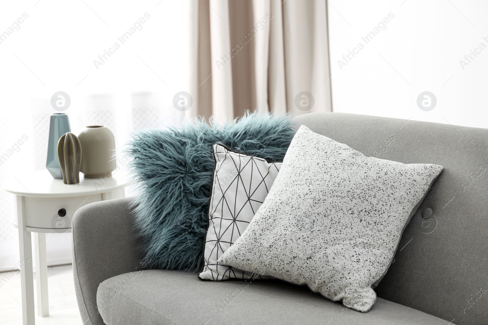 Photo of Different soft pillows on sofa in room. Interior element