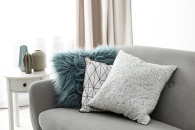 Different soft pillows on sofa in room. Interior element