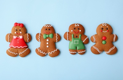 Photo of Christmas human shaped gingerbread cookies on light blue background, flat lay
