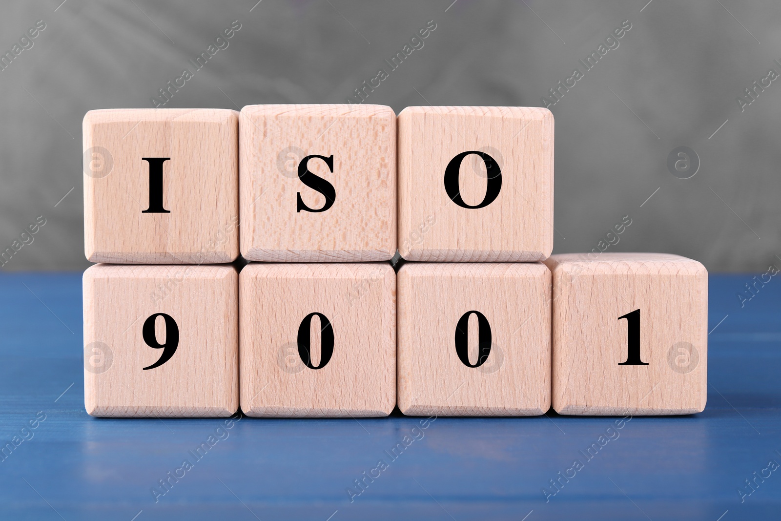 Photo of International Organization for Standardization. Cubes with abbreviation ISO and number 9001 on blue wooden table