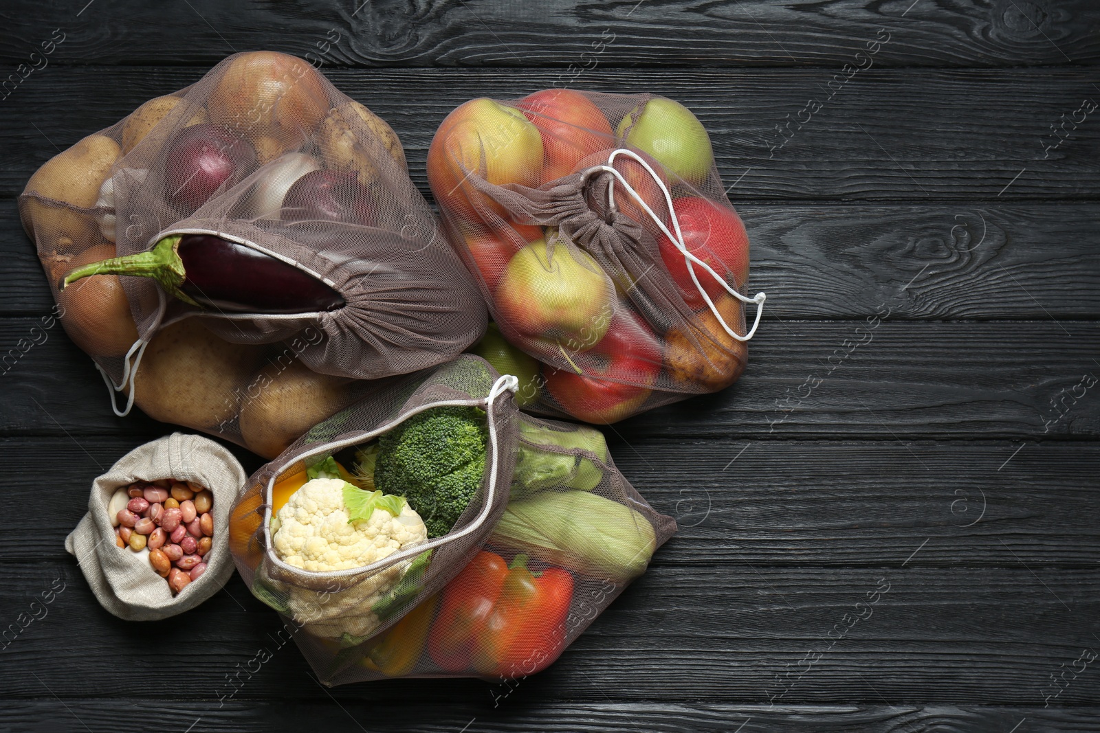 Photo of Different fresh vegetables in bags on black wooden table, flat lay and space for text. Farmer harvesting