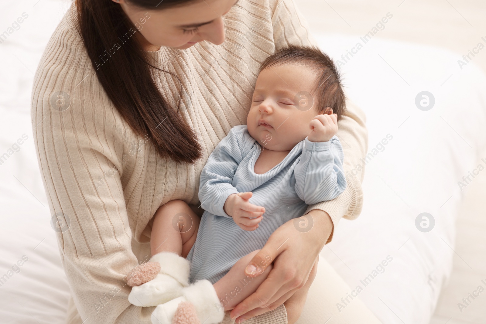 Photo of Mother with her sleeping newborn baby on bed at home, closeup