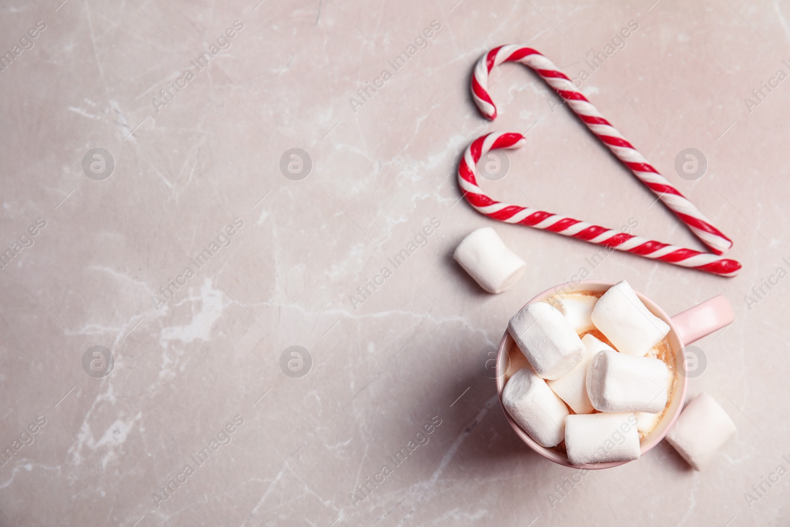 Photo of Flat lay composition with tasty candy canes, cup of hot drink and space for text on table