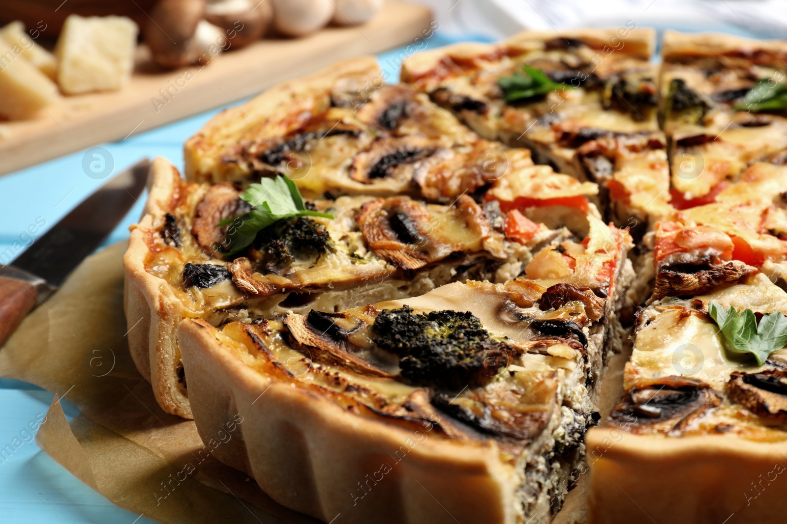 Photo of Delicious quiche with mushrooms on light blue table, closeup