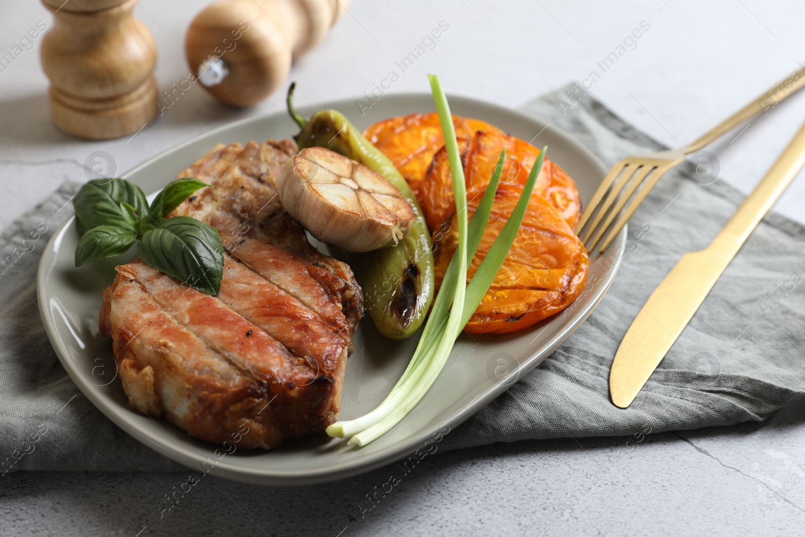 Photo of Delicious grilled meat and vegetables served on light grey table, closeup