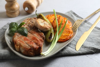 Photo of Delicious grilled meat and vegetables served on light grey table, closeup