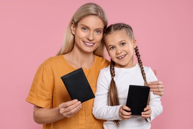 Immigration. Happy woman and her daughter with passports on pink background